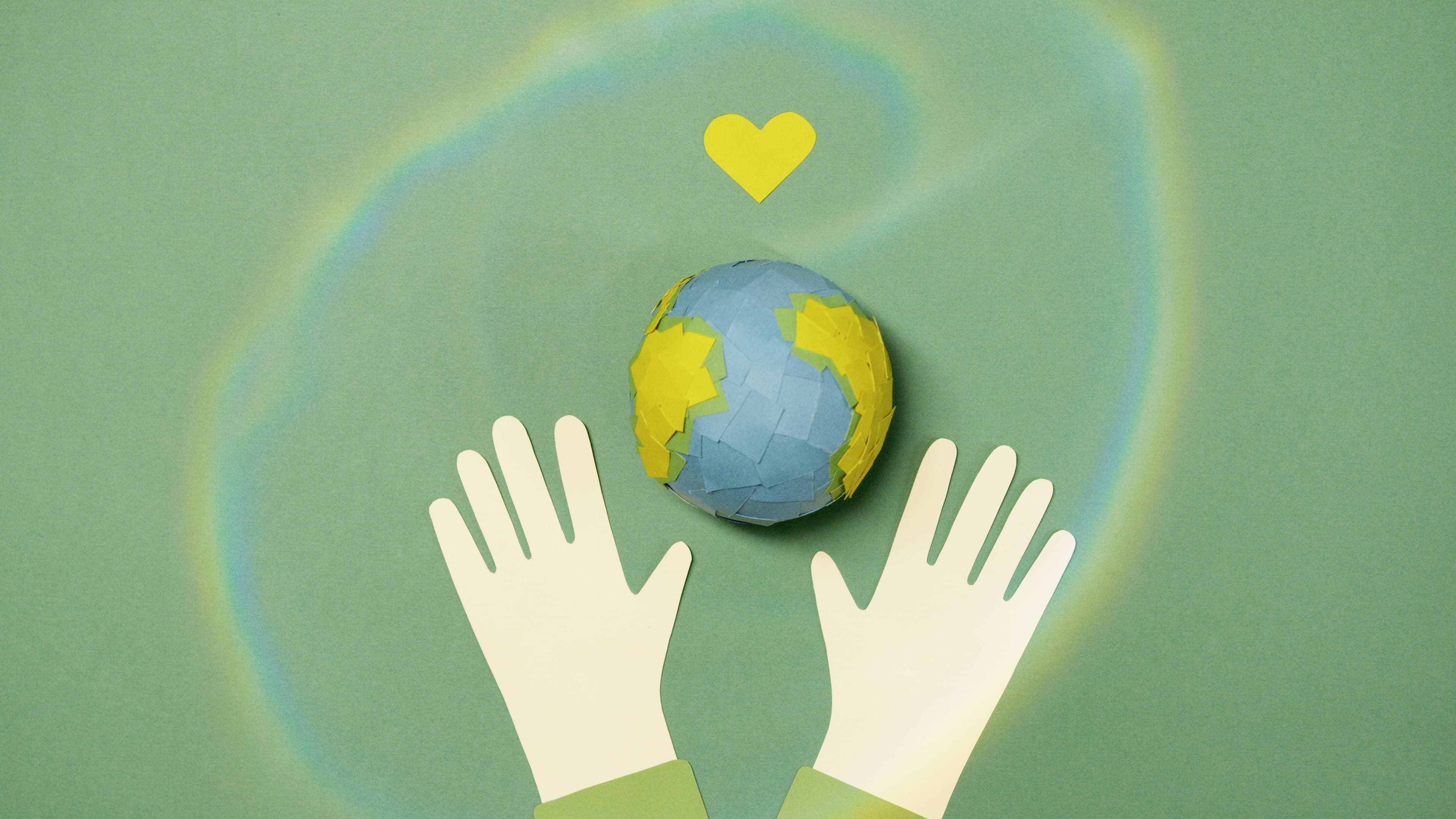 Paper-cut hands reaching toward a globe with a yellow heart
